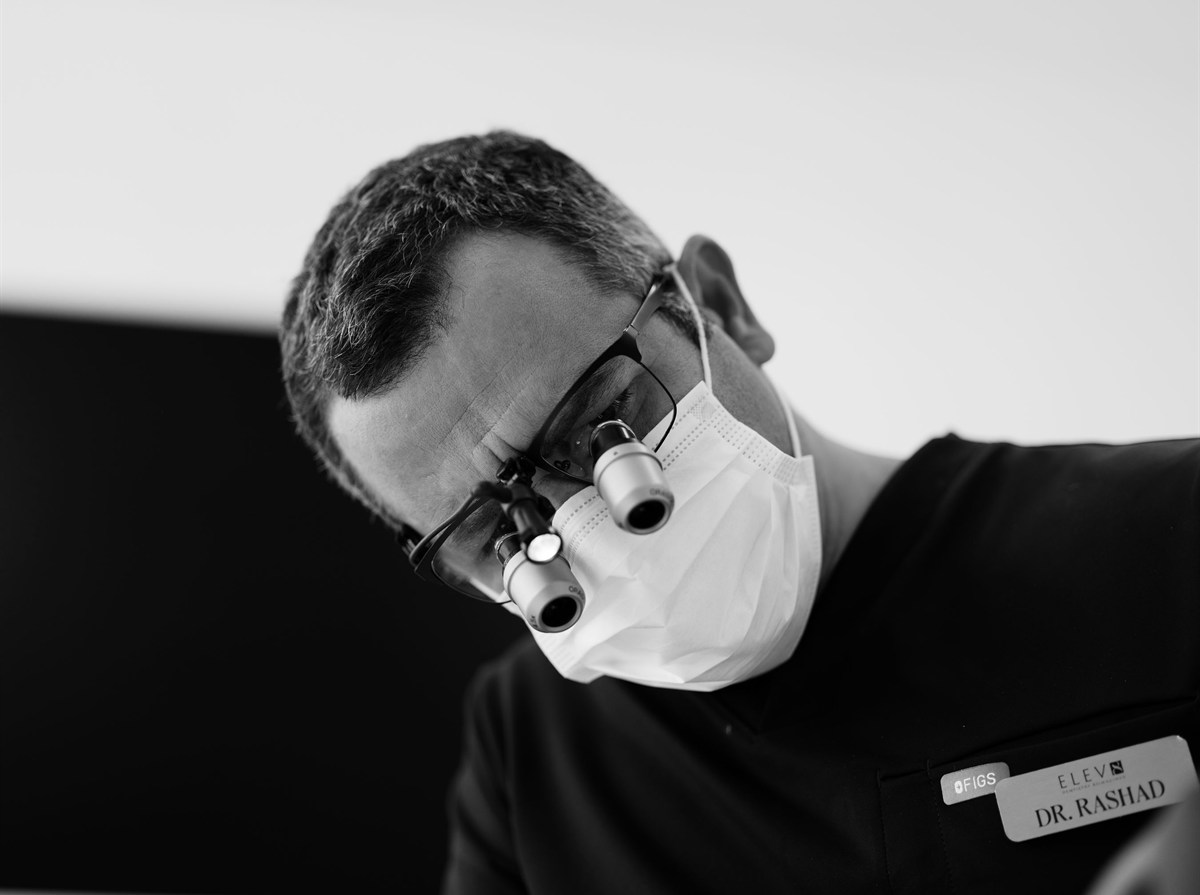 An ELEV8 dentist wearing surgical loupes and mask during magnified decay removal in Beverly Hills